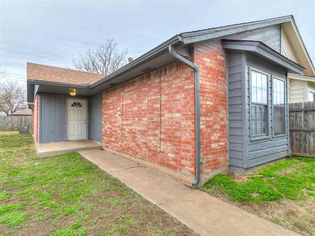 view of side of home with brick siding and fence