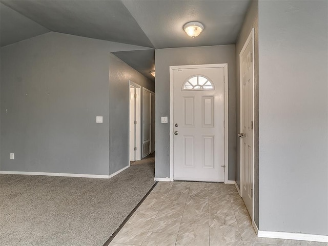 entryway with lofted ceiling, light carpet, and baseboards