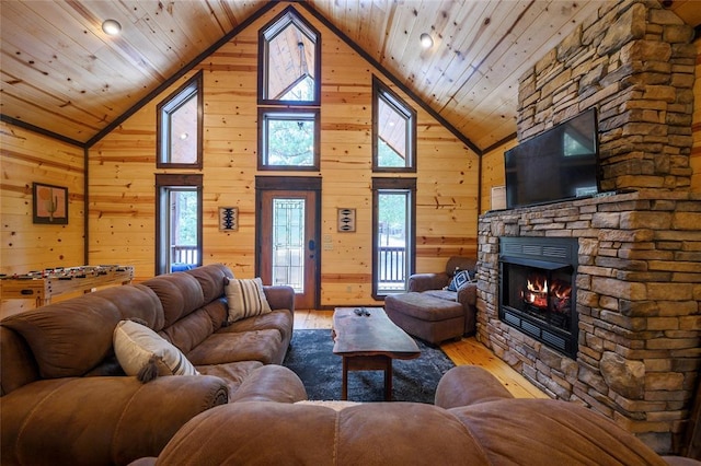 living room with a stone fireplace, hardwood / wood-style flooring, wooden walls, and wooden ceiling