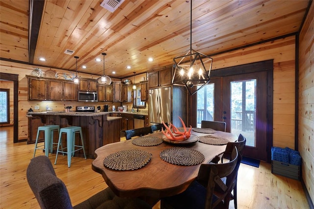 dining area with wooden walls, wood ceiling, visible vents, and light wood-style flooring