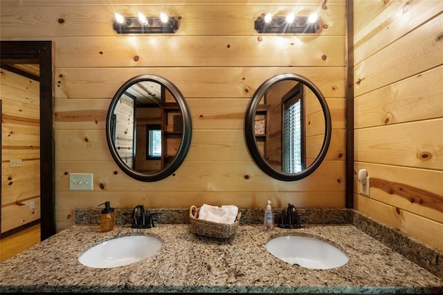 bathroom featuring double vanity, wood walls, and a sink