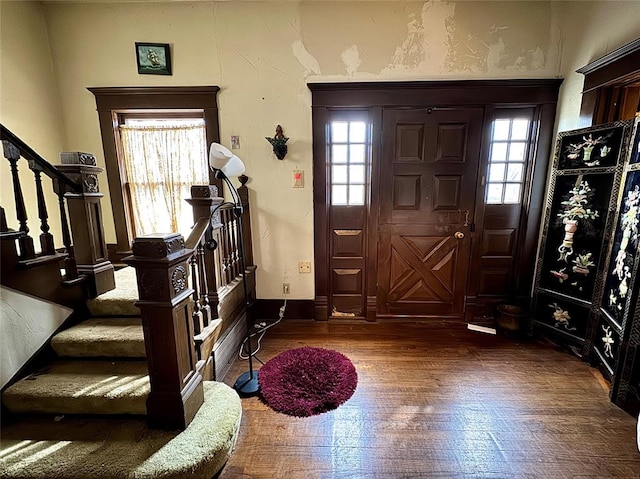 foyer entrance with stairs, wood finished floors, and a healthy amount of sunlight