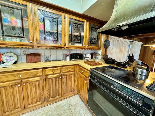 kitchen with brown cabinets, black range with electric cooktop, island range hood, and light countertops