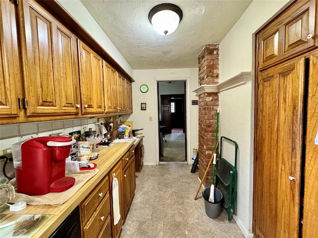 kitchen with brown cabinetry, baseboards, light countertops, a textured ceiling, and backsplash