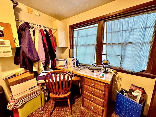 office with built in desk and a textured ceiling