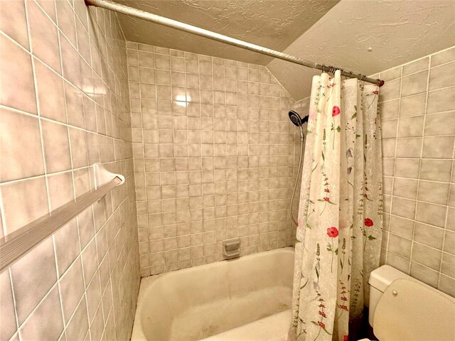 bathroom with a textured ceiling, toilet, and shower / tub combo