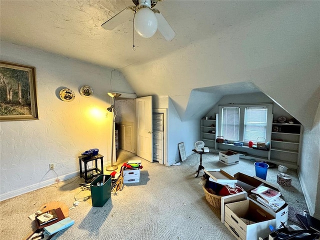 interior space featuring a textured ceiling, carpet, lofted ceiling, ceiling fan, and a textured wall