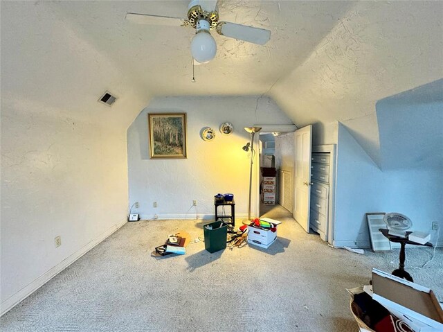 additional living space featuring visible vents, baseboards, vaulted ceiling, light carpet, and a textured ceiling