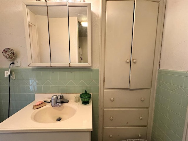 bathroom with a wainscoted wall, tile walls, and vanity