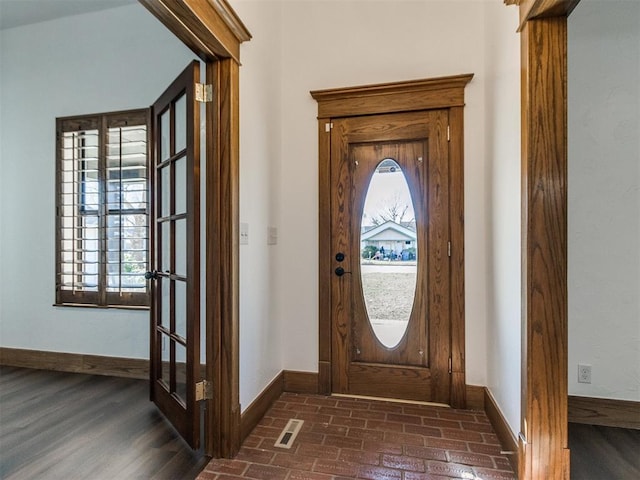 entrance foyer with brick floor, visible vents, and baseboards