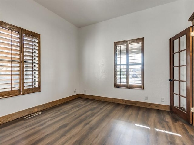 spare room featuring visible vents, baseboards, and wood finished floors