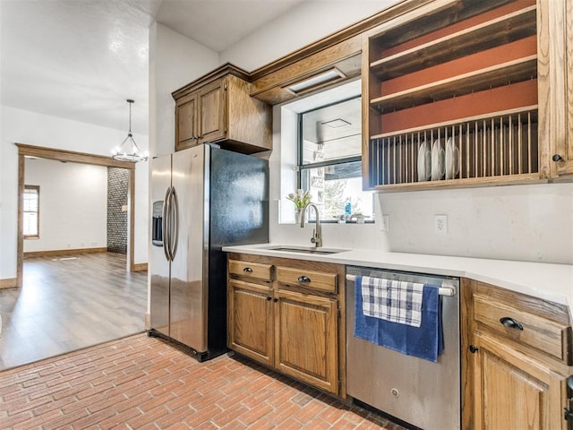 kitchen with stainless steel appliances, light countertops, a sink, and baseboards