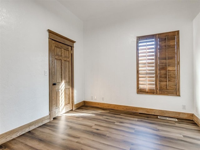 unfurnished room featuring visible vents, baseboards, and wood finished floors