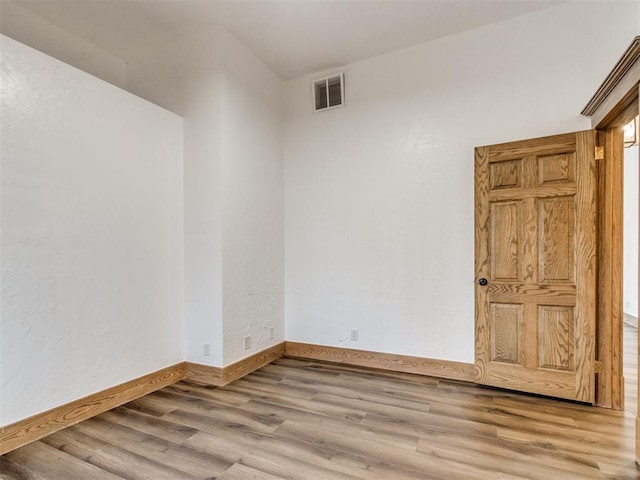 empty room featuring wood finished floors, visible vents, and baseboards