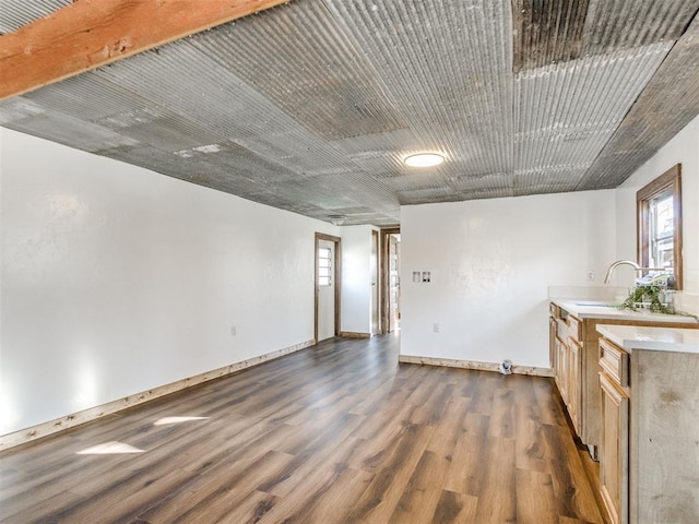 unfurnished room with dark wood-style flooring, a sink, and baseboards