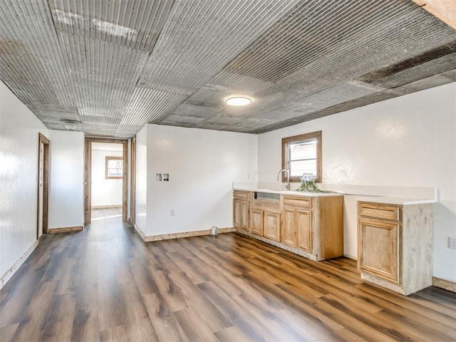 kitchen with light countertops, light brown cabinetry, dark wood finished floors, and baseboards