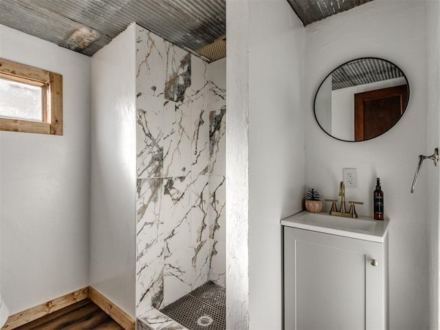 full bath with baseboards, vanity, a marble finish shower, and wood finished floors