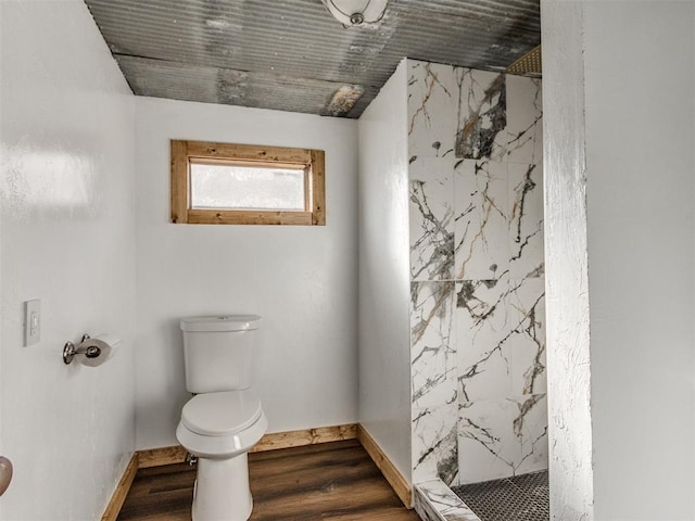 bathroom with toilet, a marble finish shower, baseboards, and wood finished floors