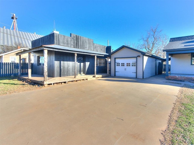 view of front of house with an outbuilding, a detached garage, driveway, and fence