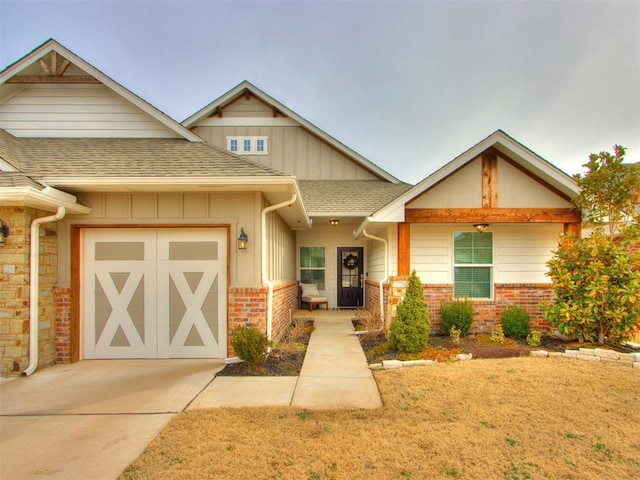 craftsman-style home featuring a garage, concrete driveway, roof with shingles, board and batten siding, and brick siding