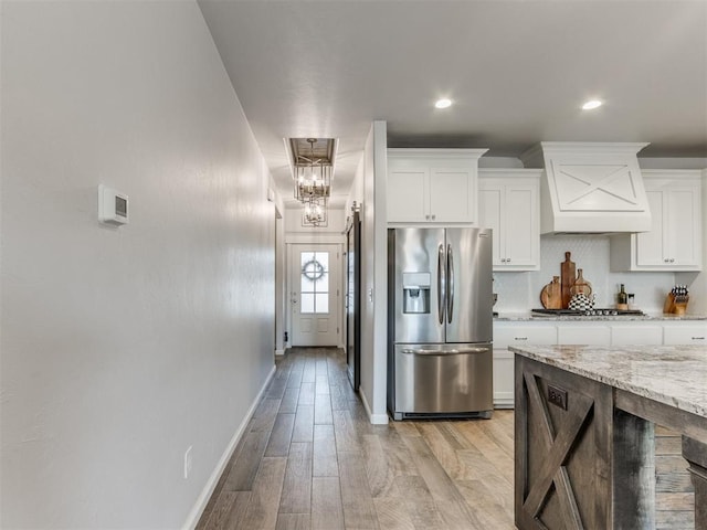 kitchen with stainless steel appliances, light wood finished floors, white cabinetry, and light stone countertops