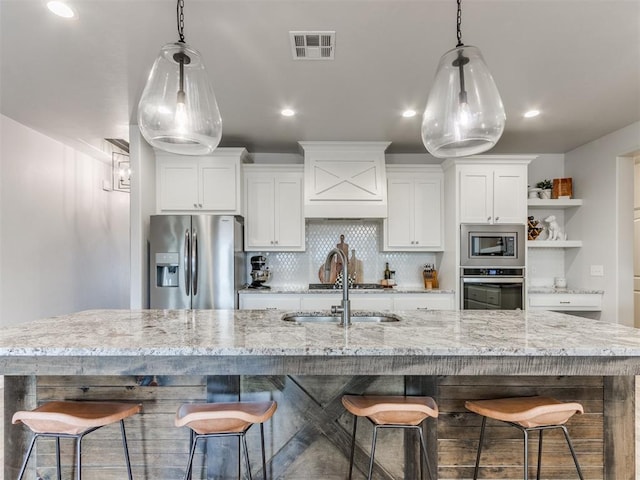 kitchen with visible vents, backsplash, appliances with stainless steel finishes, white cabinets, and a sink