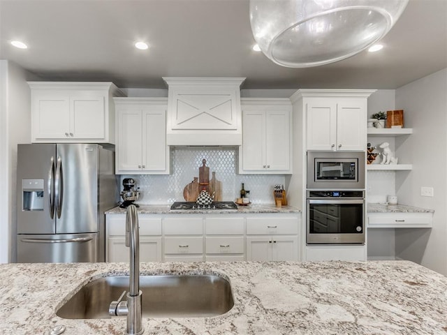 kitchen with stainless steel appliances, a sink, white cabinetry, decorative backsplash, and open shelves