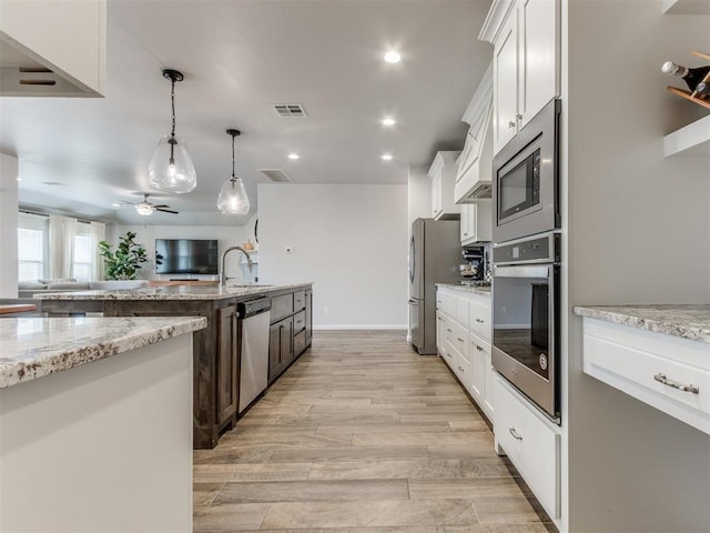 kitchen featuring appliances with stainless steel finishes, open floor plan, visible vents, and decorative light fixtures