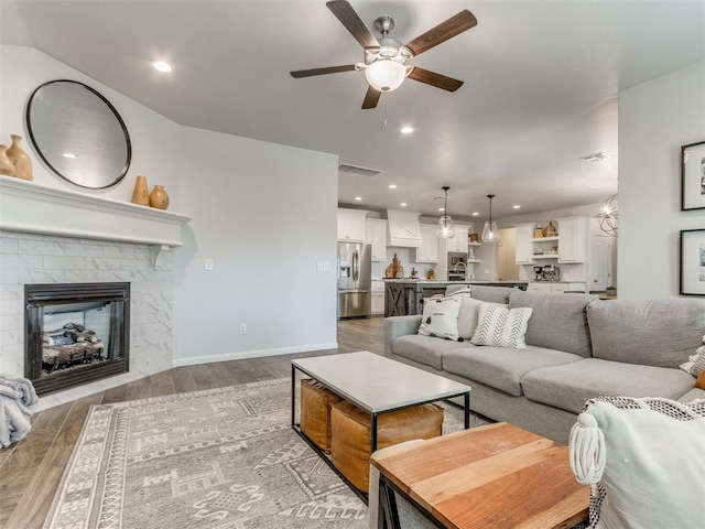 living area with light wood-style floors, a glass covered fireplace, visible vents, and recessed lighting