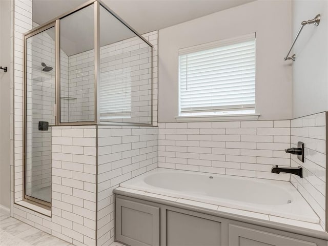 full bathroom featuring marble finish floor, a stall shower, and a bath