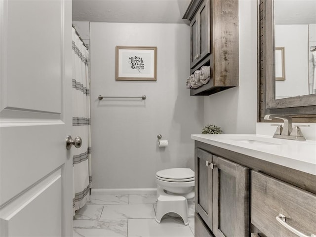 bathroom with marble finish floor, toilet, vanity, and baseboards