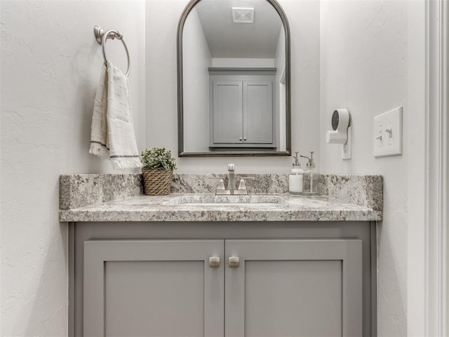 bathroom with visible vents, a textured wall, and vanity