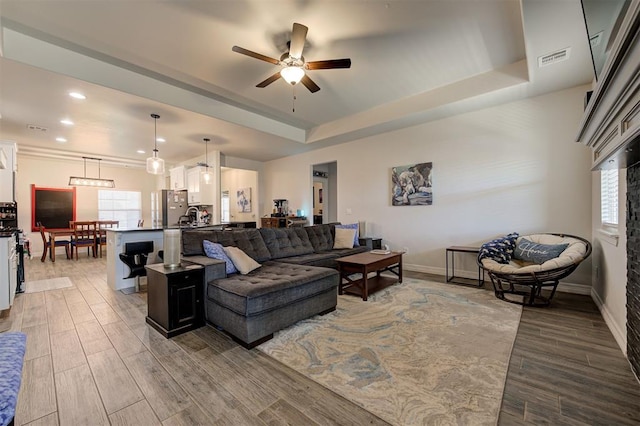 living area with a wealth of natural light, a raised ceiling, and wood finished floors