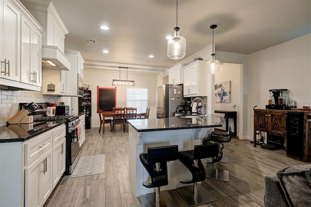 kitchen featuring stainless steel appliances, wood finished floors, backsplash, and white cabinets