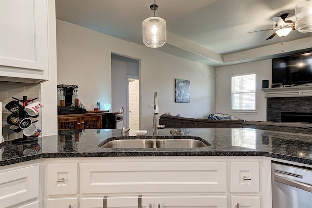 kitchen featuring open floor plan, white cabinetry, a sink, and dark stone countertops