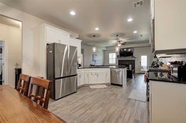 kitchen featuring visible vents, appliances with stainless steel finishes, open floor plan, a sink, and a peninsula