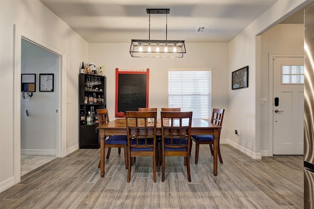 dining area featuring baseboards, visible vents, and wood finished floors