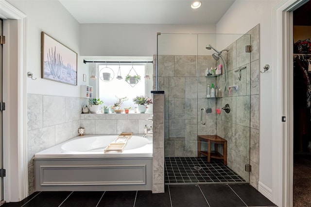 bathroom featuring a walk in closet, a garden tub, tile walls, a stall shower, and tile patterned flooring