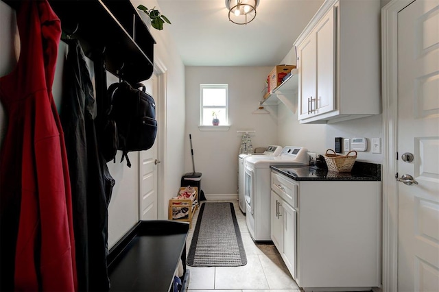 laundry area with light tile patterned floors, cabinet space, baseboards, and washer and dryer