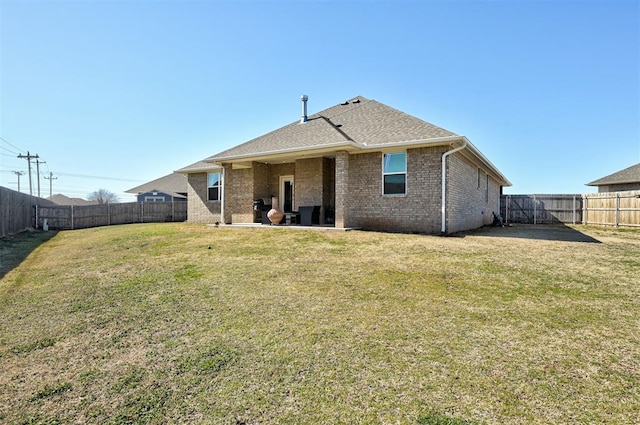 back of house featuring a patio, a fenced backyard, brick siding, roof with shingles, and a lawn