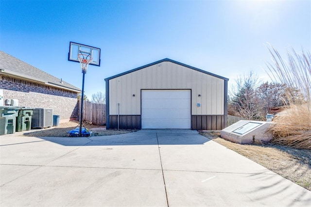 detached garage featuring driveway, fence, and cooling unit