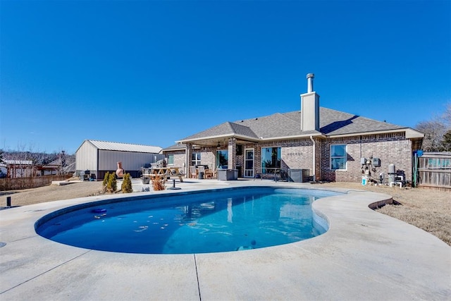 view of swimming pool featuring fence, an outdoor structure, a fenced in pool, and a patio