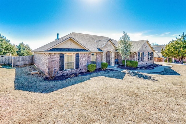 view of front of property featuring brick siding, a front yard, and fence