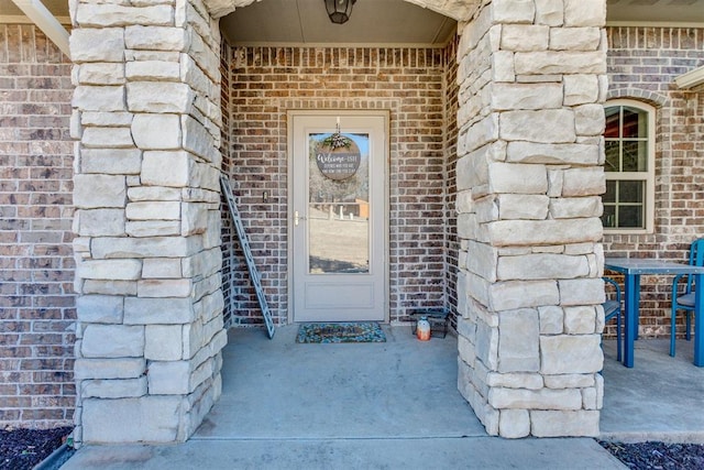 doorway to property featuring stone siding and brick siding