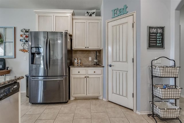 kitchen featuring dark stone counters, stainless steel appliances, tasteful backsplash, and cream cabinets