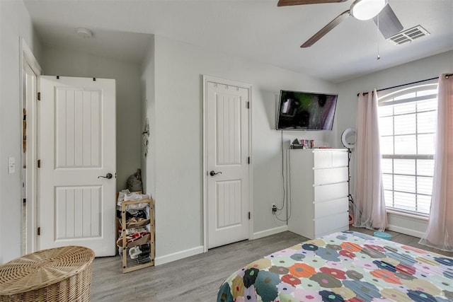 bedroom featuring lofted ceiling, wood finished floors, visible vents, and baseboards