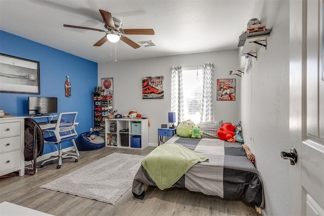 bedroom featuring a ceiling fan, visible vents, and wood finished floors