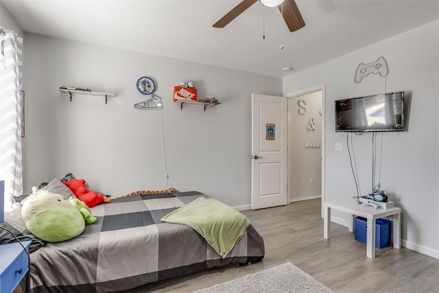 bedroom featuring a ceiling fan, baseboards, and wood finished floors