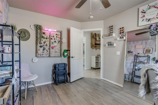 interior space featuring a ceiling fan, baseboards, and wood finished floors