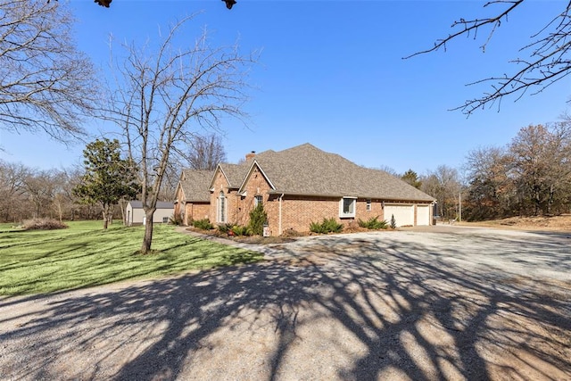 view of front of home with driveway, a chimney, an attached garage, a front lawn, and brick siding